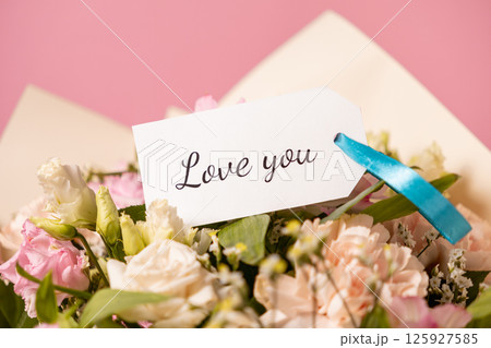 romantic bouquet of pastel flowers with a handwritten love you message card tied with a blue ribbon, expressing deep affection and devotion on a soft pink background romantic bouquet of pastel flowers with a handwritten love you message card tied with a blue ribbon, expressing deep affection and devotion on a soft pink background 125927585