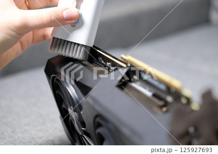 hand using soft brush to clean gpu edge connector and cooling fins to ensure better contact and dust free performance in pc hardware maintenance hand using soft brush to clean gpu edge connector and cooling fins to ensure better contact and dust free performance in pc hardware maintenance 125927693