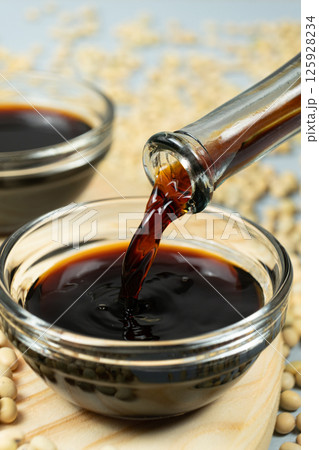 Close-up of the process of pouring soy sauce into a saucepan. Close-up of the process of pouring soy sauce into a saucepan. 125928234