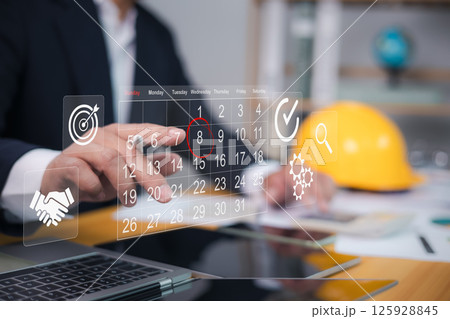Architect or engineer pointing finger at construction marking dates on virtual calendar, Project presentation plan, Construction planning, Appointment scheduler, Set reminders for important project. Architect or engineer pointing finger at construction marking dates on virtual calendar, Project presentation plan, Construction planning, Appointment scheduler, Set reminders for important project. 125928845