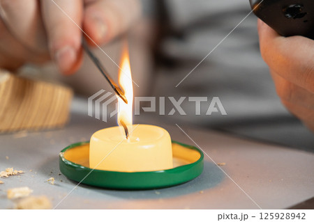 hands carefully heating a metal tool over a candle flame for a diy home repair or crafting project 125928942