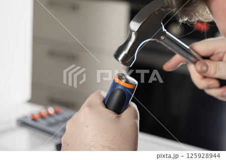 man using a hammer for a diy home repair project, close-up on hands and tools in a workshop setting 125928944