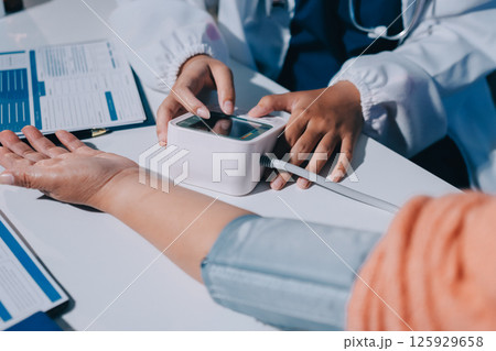 Nurse measuring blood pressure of elderly woman at table, closeup. Assisting senior generation Nurse measuring blood pressure of elderly woman at table, closeup. Assisting senior generation 125929658
