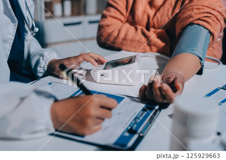 Nurse measuring blood pressure of elderly woman at table, closeup. Assisting senior generation Nurse measuring blood pressure of elderly woman at table, closeup. Assisting senior generation 125929663