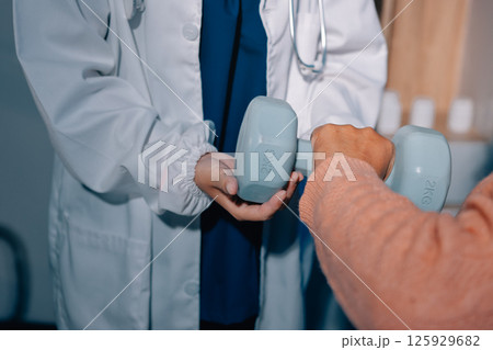 Physiotherapist training with patient using dumbbells in clinic,Physical therapy concept Physiotherapist training with patient using dumbbells in clinic,Physical therapy concept 125929682