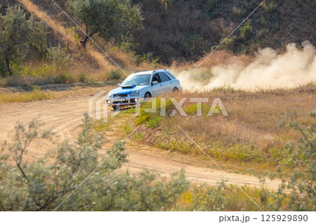 Sports Hatchback Takes a Turn on a Dirt Road 125929890