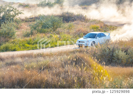 White Sports Car in Motion on a Dusty Road 125929898