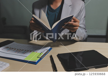 Working from home, Closeup business woman using laptop computer and analyzing financial report. 125930668