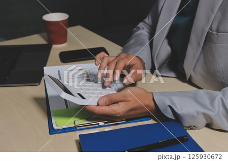 Working from home, Closeup business woman using laptop computer and analyzing financial report. 125930672