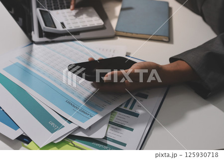 Working from home, Closeup business woman using laptop computer and analyzing financial report. Working from home, Closeup business woman using laptop computer and analyzing financial report. 125930718