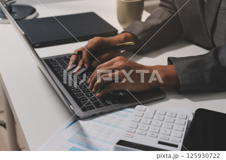 Working from home, Closeup business woman using laptop computer and analyzing financial report. Working from home, Closeup business woman using laptop computer and analyzing financial report. 125930722