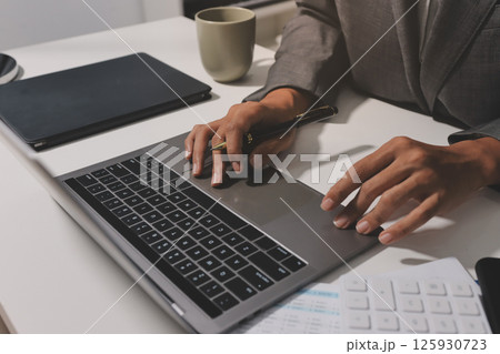 Working from home, Closeup business woman using laptop computer and analyzing financial report. 125930723