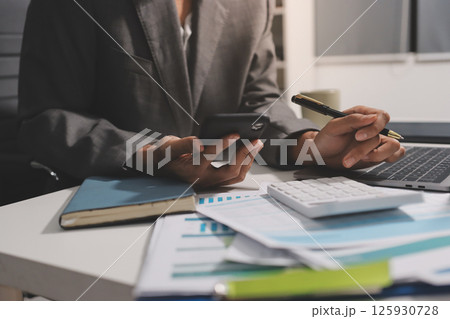 Working from home, Closeup business woman using laptop computer and analyzing financial report. 125930728