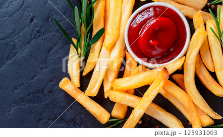 A plate of french fries with a bottle of ketchup on top 125931003