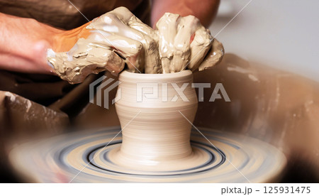 A potter's wheel is spinning a piece of clay 125931475