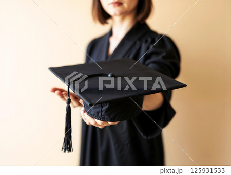A woman is holding a black cap and gown 125931533