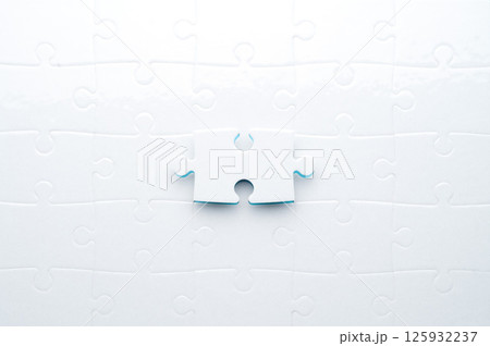 Concept for problem-solving, teamwork, solutions, or missing connections. White jigsaw puzzle on a vibrant blue background with one missing piece. Minimalist composition with copy space. Concept for problem-solving, teamwork, solutions, or missing connections. White jigsaw puzzle on a vibrant blue background with one missing piece. Minimalist composition with copy space. 125932237