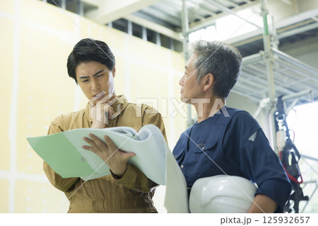 現場で図面を見ながら打ち合わせする現場監督  125932657