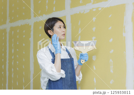 石膏ボードにパテをする女性　  125933011