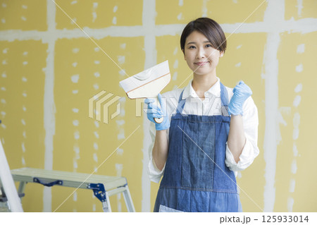 石膏ボードにパテをする女性　  125933014