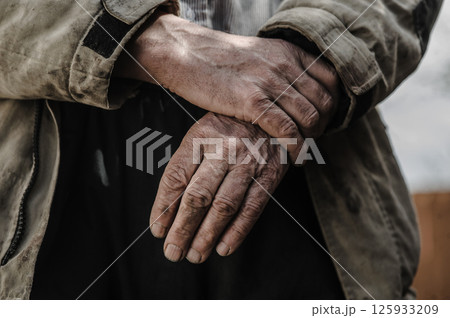 The worker's hands, covered with sweat and dust, demonstrate endless determination. 125933209