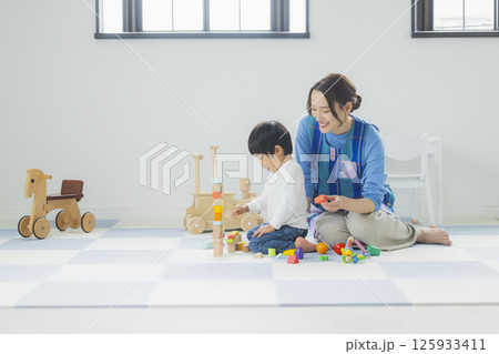 積み木で遊ぶ子供とエプロンの女性 125933411