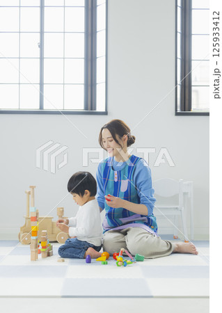 積み木で遊ぶ子供とエプロンの女性 125933412