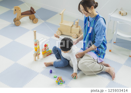 積み木で遊ぶ子供とエプロンの女性 125933414