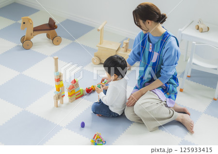 積み木で遊ぶ子供とエプロンの女性 125933415