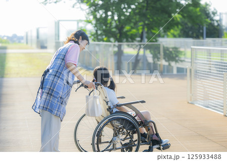 小学生が乗った車椅子を押す介護士 125933488