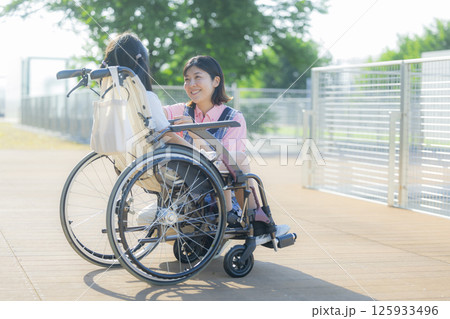 小学生が乗った車椅子を押す介護士 小学生が乗った車椅子を押す介護士 125933496