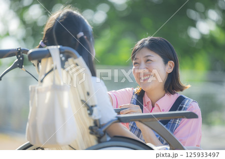 小学生が乗った車椅子を押す介護士 小学生が乗った車椅子を押す介護士 125933497