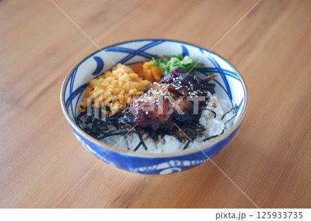 a beautifully arranged Japanese rice bowl served in a traditional patterned ceramic bowl 125933735