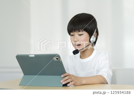 ヘッドセットをつけてタブレットPCに向かう小学4年生の男の子 125934188