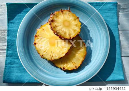 Slice of pineapple on a blue plate 125934481