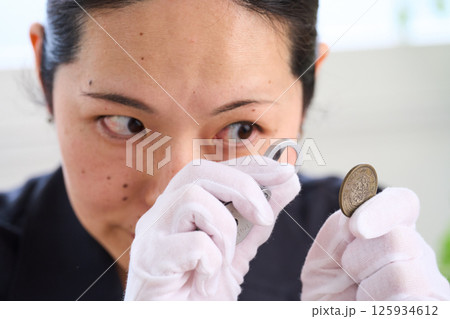 古銭を鑑定する女性 鑑定士 古銭を鑑定する女性 鑑定士 125934612