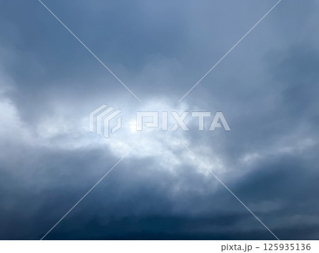 重く垂れこめる曇天の空と淡い光 125935136
