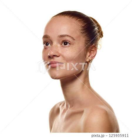 Portrait of young attractive woman with well-kept skin and freckles, looking upwards over white background. Portrait of young attractive woman with well-kept skin and freckles, looking upwards over white background. 125935911