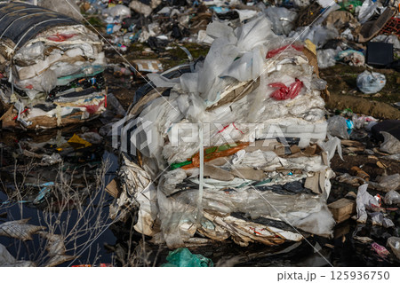 Piles of waste and plastic bags are found near a river, highlighting environmental neglect and the urgency for better waste management solutions Piles of waste and plastic bags are found near a river, highlighting environmental neglect and the urgency for better waste management solutions 125936750