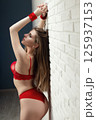 a girl in a body with a beautiful red underwear on a simple background of a white brick wall 125937153