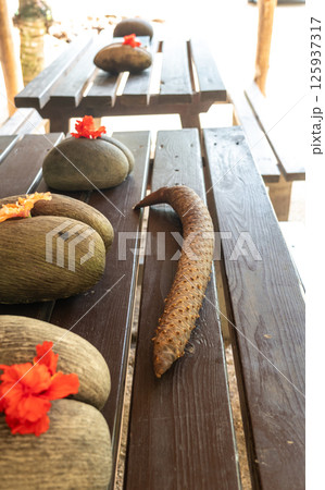 Coco de Mer seeds and male inflorescence displayed with hibiscus flowers on a wooden table 125937317