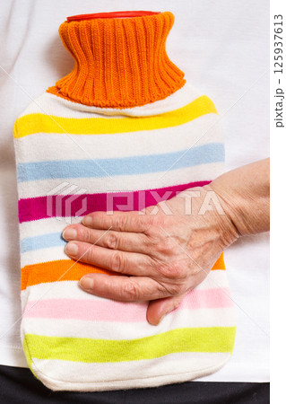 Senior woman with hot water bottle on her back. Help with pain in old age Senior woman with hot water bottle on her back. Help with pain in old age 125937613