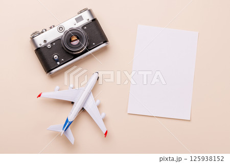 Travel-themed flat lay with blank photo card, camera, toy airplane 125938152