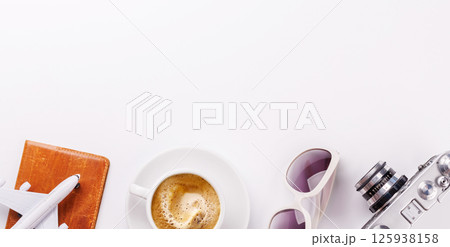 Travel-themed flat lay with toy airplane, camera, and coffee 125938158