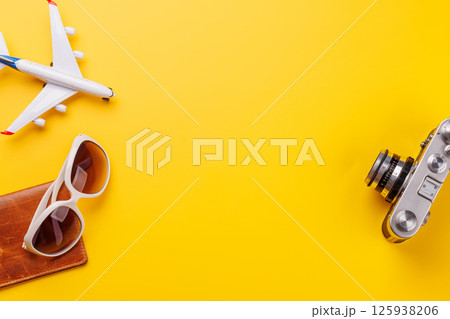 Travel-themed flat lay with toy airplane, camera, and sunglasses 125938206