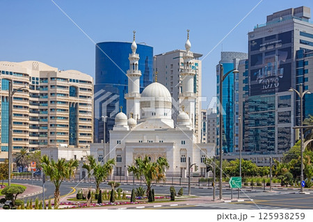 White mosque between modern highrises in urban Dubai contrast White mosque between modern highrises in urban Dubai contrast 125938259