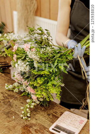 Florist arranging bouquet of flowers on wooden table, Mothers day 125938810
