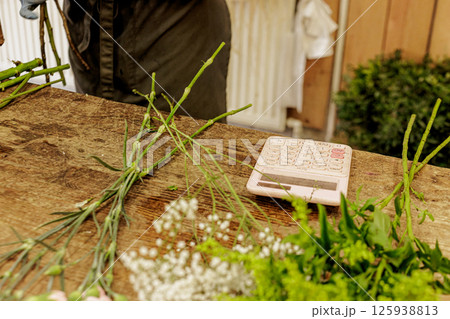 Florist arranging flowers and calculating costs on wooden table Florist arranging flowers and calculating costs on wooden table 125938813