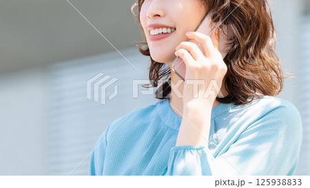 スマートフォンで話す笑顔の女性・ビジネスウーマン 125938833