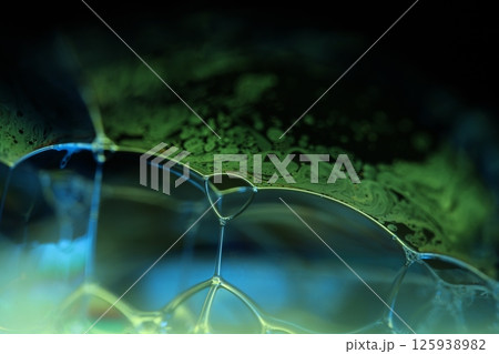 Green and blue liquid surface, green Reflections of liquid in macro,, bubbles in macro, connection of bubbles in macro, cell from liquid, dark background, glossy surface 125938982